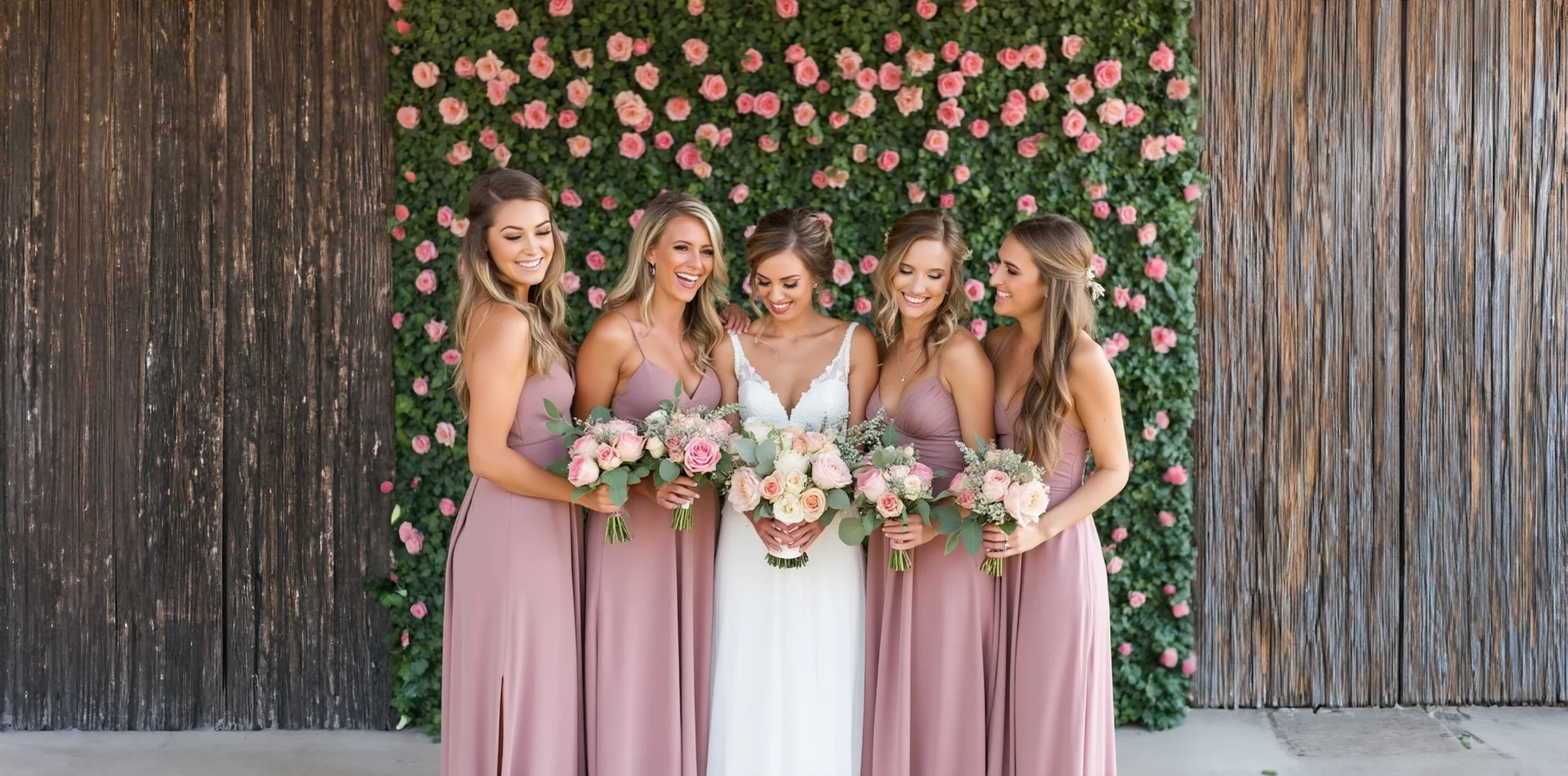 Bridal party celebrating in front of a Lush flower wall